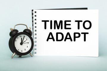 A words TIME TO ADAPT on notebook with clock. Concept for time management and business.