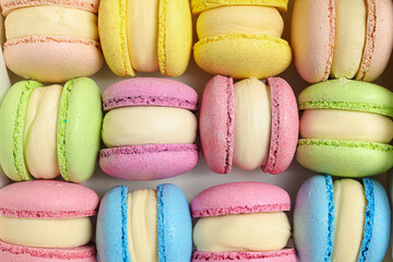 Many delicious colorful macarons on white background, top view
