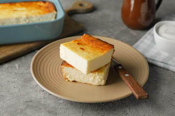 Plate with pieces of cottage cheese casserole on grunge background