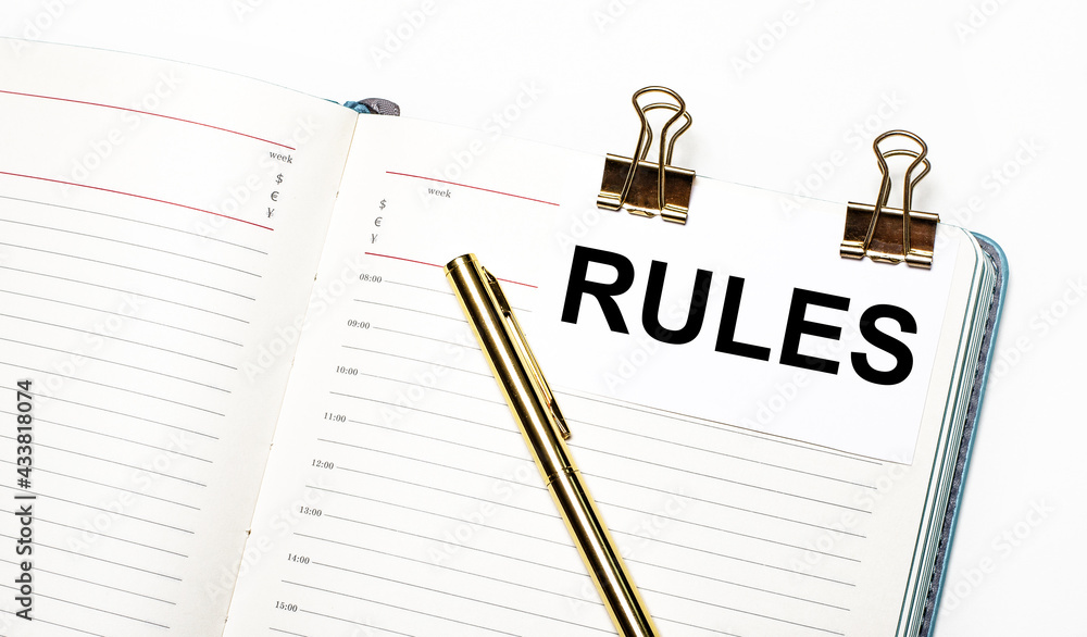 Poster on a light background, an open notebook, a sheet of paper with gold clips and the text rules and a g