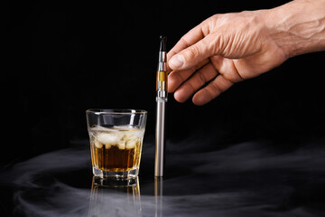 Male hand with electronic cigarette and glass of whisky on dark background