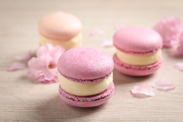 Pink macarons and flowers on white wooden table