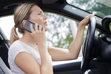 woman talking on cell phone while driving her car
