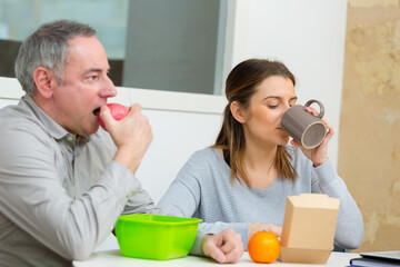 middle aged business colleagues eating in office