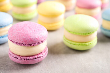 Many delicious colorful macarons on grey table, closeup