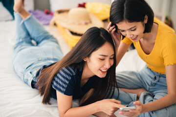 Young beautiful Asian couple love friend woman look at smartphone on bed at hotel room when summer trip which smiling and felling happy, LGBT woman love Travelling summer vacation trip concept