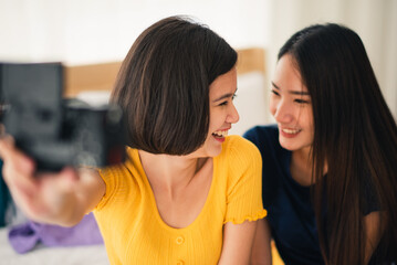 Young beautiful Asian couple love friend woman take picture selfie by digital camera on bed when summer trip which smiling and felling happy, LGBT woman love Travelling vacation trip concept