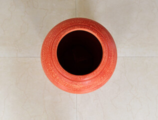 Squares, rectangles and circles. A red ceramic pot on tiled floor. view from top. Terracotta pot for interior decoration. Geometric lines and patterns..