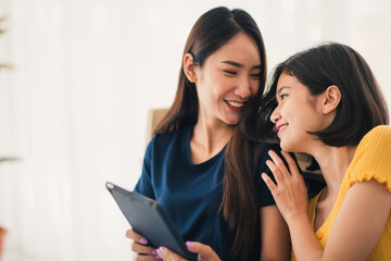 Young beautiful Asian couple love friend woman looking at tablet and touch hand on bedroom at home which smiling and felling happy, LGBT woman love Travelling summer vacation trip concept.
