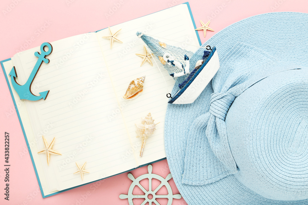 Wall mural Summer straw hat with notepad and seashells on pink background