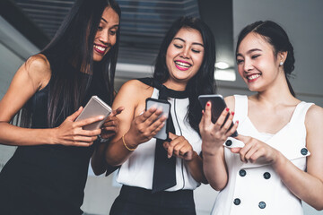 Three women friends having conversation while looking at mobile phone in their hands. Concept of...