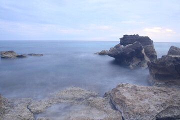 Paisaje del mar con rocas y agua efecto seda al atardecer con el cielo nublado, Mallorca