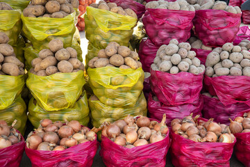 Potato and onion in plastic bags on bazaar market place.