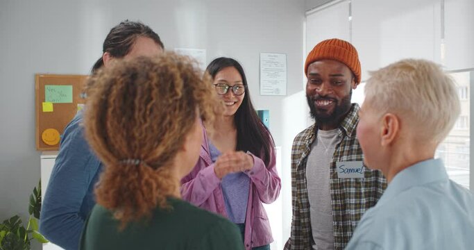 Multiethnic positive people hugging during therapy session in support meeting