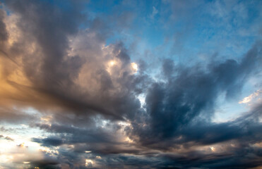 Multicolored, black clouds on a dramatic blue background sky