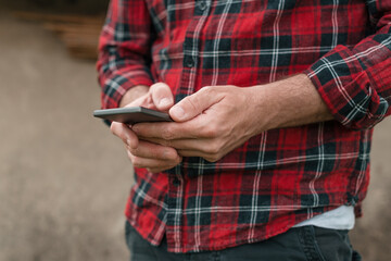 Farmer using smart phone app at the farm, close up of hands with selective focus
