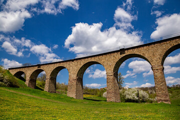 Fototapeta na wymiar Old railway stone viaduct in the spring in sunny day.