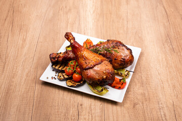 Grilled chicken with vegetable garnish served in a white plate on wooden table. Copy space.