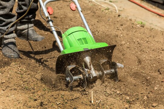 Gardening. Spring work on the farm. Land cultivation with an electric cultivator. Man plows the earth with an electric cultivator.