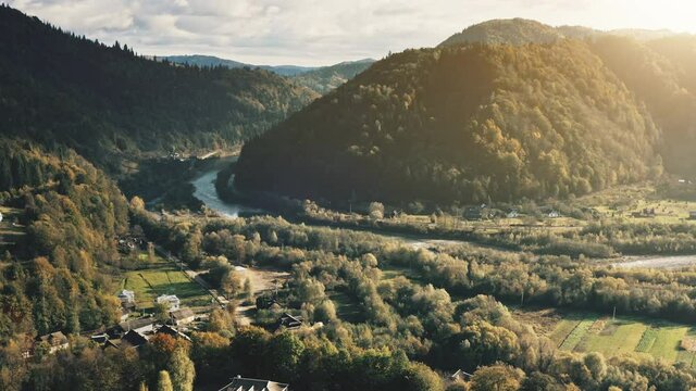 Sun mountain valley with village on river shore aerial view. Isolated coutryside town at nature landscape. Cottages at farmland fields. Spruce forest at Peneda Geres National Park, Portugal, Europe