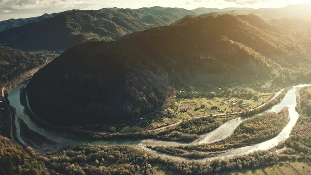 Sunrise over river at mountain valley aerial. Water flow at coutryside town. Village at stream shore. Rural green grass fields at cottages. Pine forest in Europe, Portugal, Peneda Geres National Park