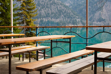 Street cafe with simple wooden furniture on the shore of a picturesque mountain lake.