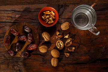 Food for iftar in ramadan on a wooden table dates, nuts and water.