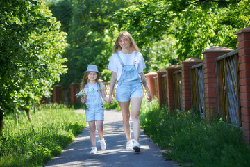 Mother walking with daughter in public park at sunny day