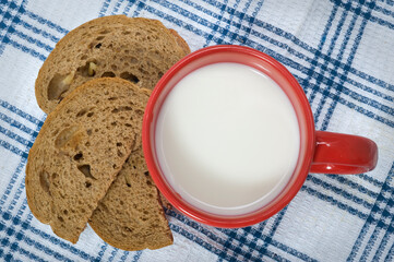 Breakfast  in the morning. Fresh bread and a red cup of milk.