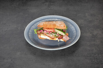 Sandwich with  Light bread, with cucumber, tomato, and bacon, for breakfast or light lunch, gray plate, and dark background.