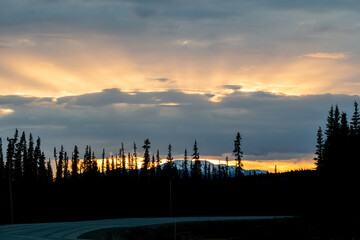 Stunning sunset rays shining bright along the Alaska Highway during springtime in northern Canada. 