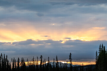 Fototapeta premium Stunning sunset rays shining bright along the Alaska Highway during springtime in northern Canada. 