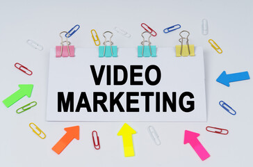 On the table there are paper clips and directional arrows, a sign that says - VIDEO MARKETING