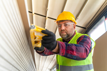 Builder in working uniform with protective helmet standing with instruments at the construction...