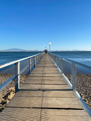 Wooden fishing pier view in San Rafael, Mendoza. Close up of the dock and background of the lake and the mountains on a clear summer day.