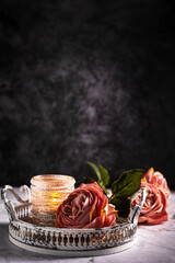 Drei Rosen in Alt Rose' Farben und Kerzenständer mit Perle liegen auf dem Marmorhintergrund, auf dem weißen Tablett aus Metall. Vintage, Hochformat, oben viel Platz zum Schreiben,  Stillleben.