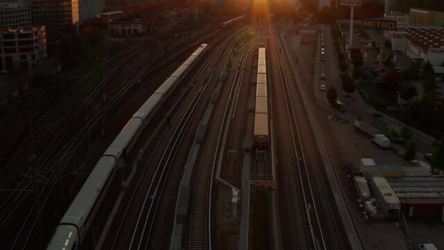 Beautiful Establishing Shot of white passenger Train on driving into Sunset over Berlin, Germany Golden Hour Cityscape and Ostbahnhof Central Train Station, Aerial Wide Angle 