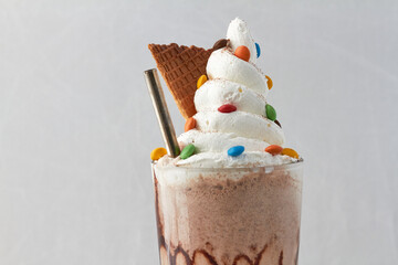 Sundae visto desde frente, con crema batida, rockets ,una bombilla y un trozo de cucurucho sobre un fondo blanco