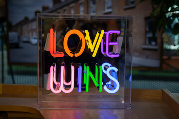 A bright colourful neon sign that says Loves Wins