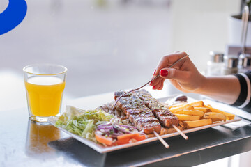 greek foods, grilled meat, and kebab, Souvlaki served with fried potatoes, tzatziki dip, and pita bread, greek cuisine, and greek salad, top view with a fork on hand.