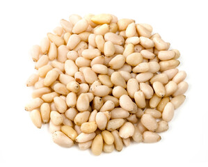 handful of unpeeled pine nuts closeup on white