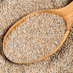 crushed rye groats in wood spoon closeup