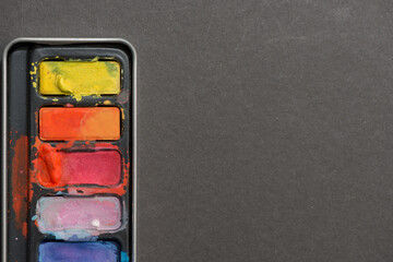 palette of pan paints on a grey background