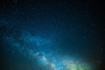 Milky Way. Night starry sky. light nebula, clouds. Shimmering blue tones. Orange glow in the sky. Blank space for your signature. Background. Texture. Color photo.