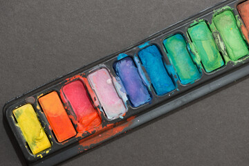 palette of pan paints on a grey background