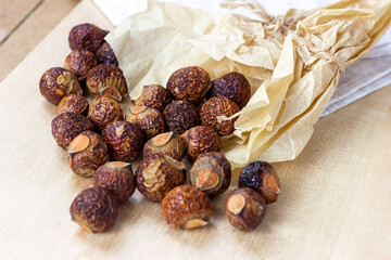 Brown dry soap nuts (Soapberries, Sapindus Mukorossi) for organic laundry and gentle natural skin care on light background.
