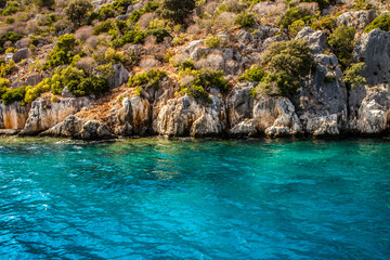 Fototapeta na wymiar Rocky coast of the Mediterranean Sea. Azure water and steep rocky coast covered with vegetation.