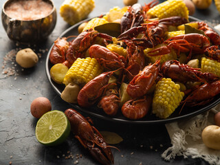 Assorted corn and crayfish. In the background is a gravy boat with sauce. White napkin. Dark...