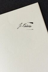 rubber stamp impression (in black ink) with the words or expression je t'aime on paper