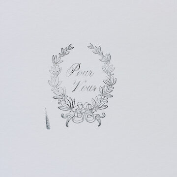 rubber stamp impression of a decorative floral motif with the message in french of pour vous (for you) on white paper